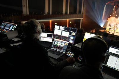 Technikregie mit Laptops und Monitoren während einer Veranstaltung im Saal