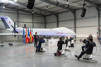 Veranstaltung in einer Flugzeughalle mit Gästen, Flaggen und Podium