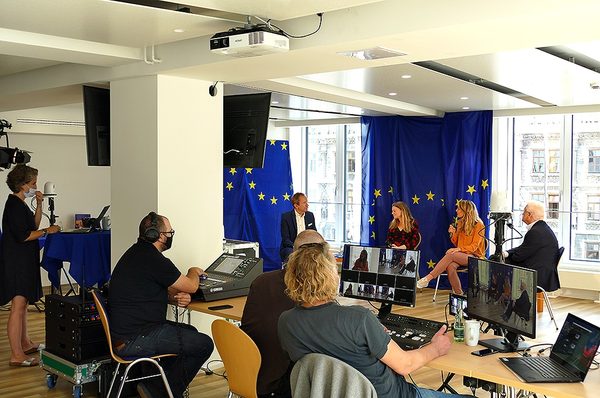 Referenz Europäische Kommission: Diskussionsrunde vor EU-Flaggen mit Regieplatz, Laptops und Monitoren für den Livestream
