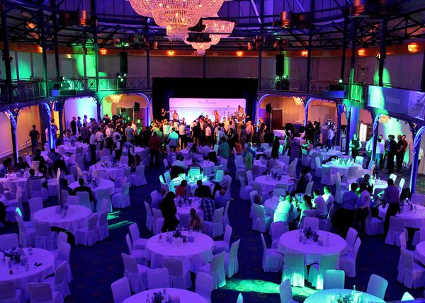 Gala mit festlich gedeckten Tischen und farbiger Lichtstimmung unter Kronleuchtern